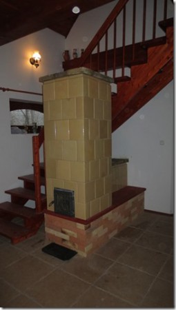 Sukorón, bontott csempéből YTONG talpazatra épített zsák kályha, a talpazat és a fedések szeletelt téglával burkolva.Különlegessége az alsó kéménybekötés, mely az ülőpadka háttámláját képezi. 